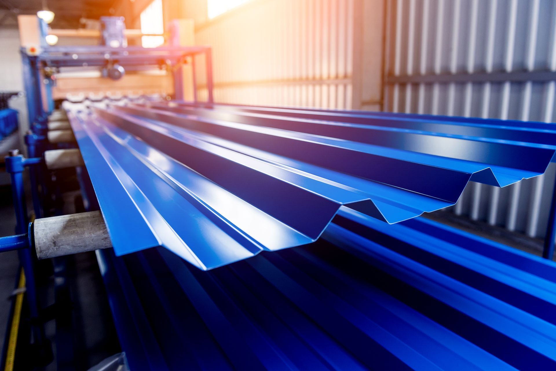A stack of blue metal sheets on a conveyor belt in a factory.
