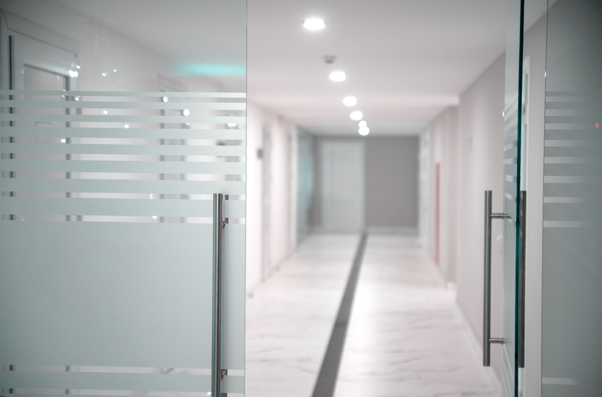 A blurred image of a hallway in an office building with glass doors.