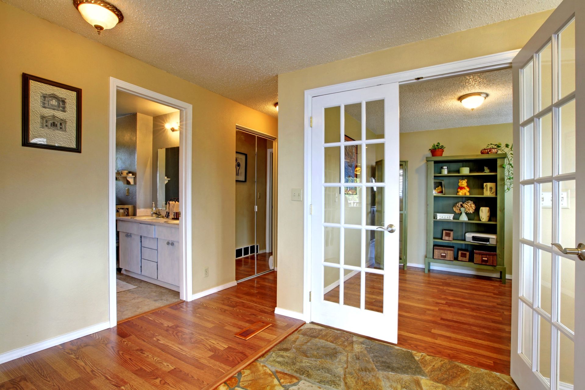 A hallway in a house with hardwood floors and french doors