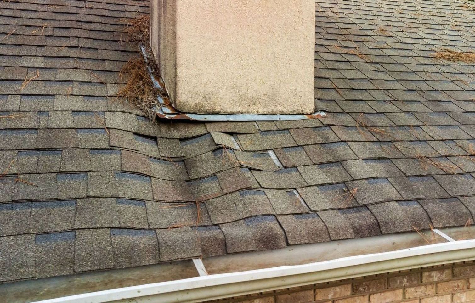 A chimney is sitting on top of a roof with shingles missing