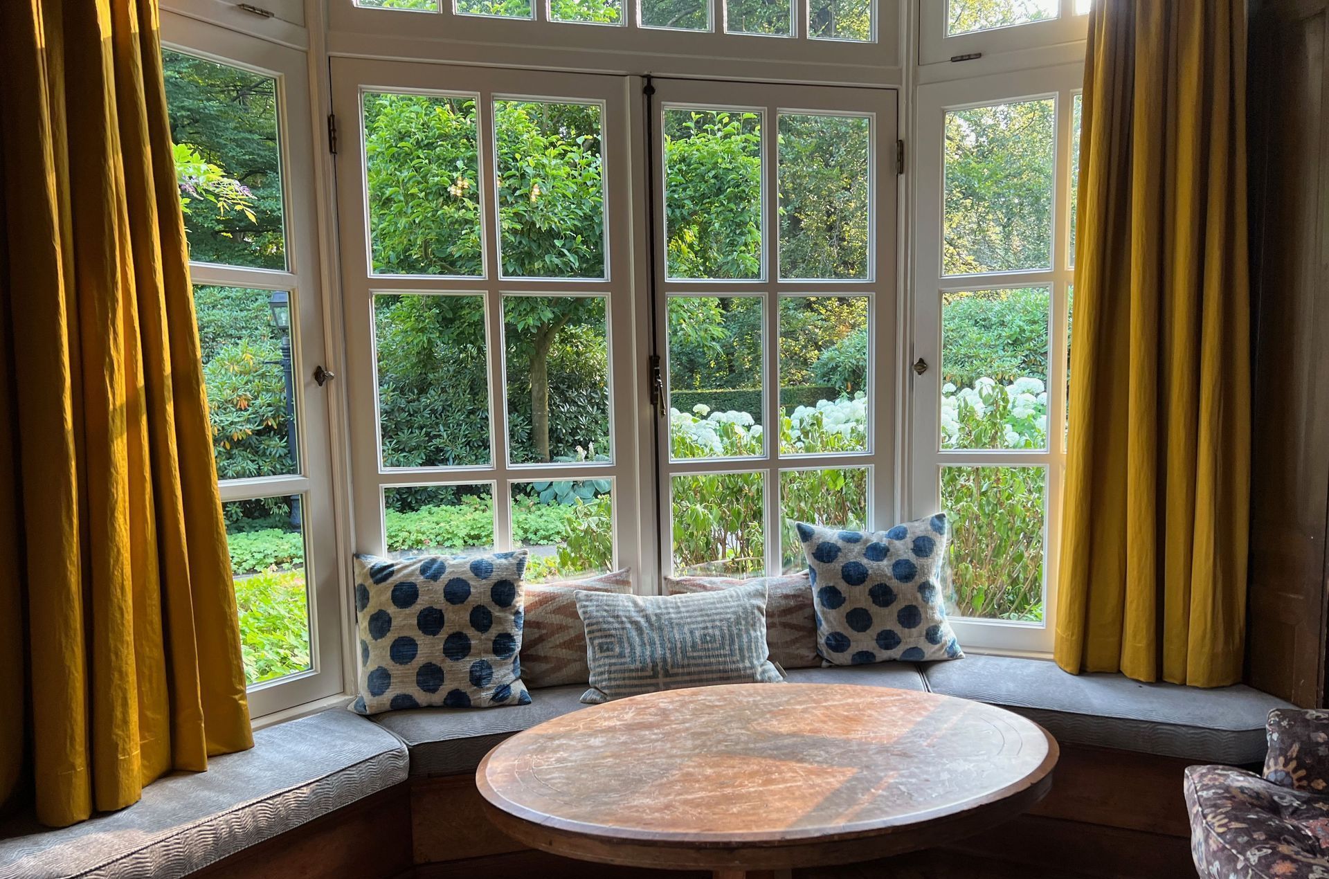 A living room with a round table in front of a large window.