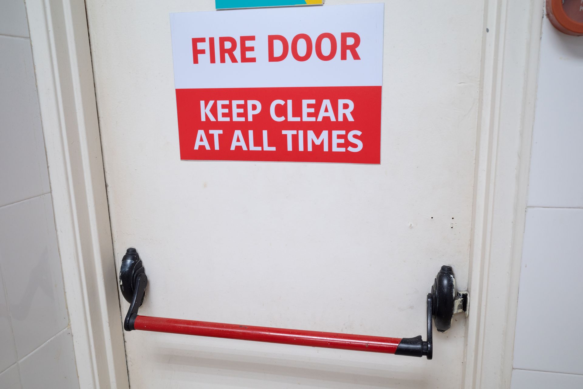 A white door with a sign on it that says fire door keep clear at all times