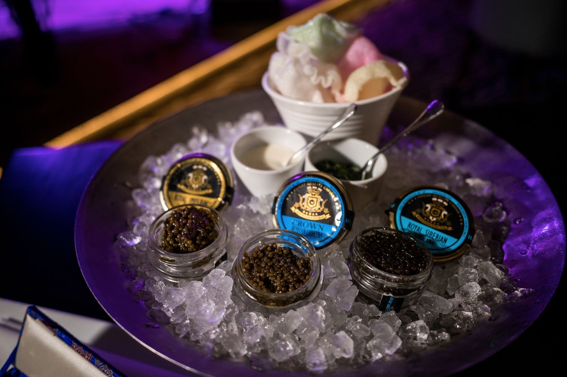 Caviar tasting: jars of caviar with ice and ice cream scoops in a bowl.