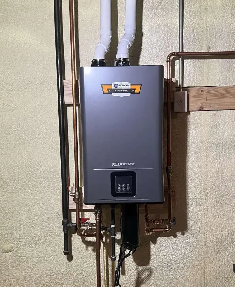 Wall-mounted gray tankless water heater with pipes in a utility room