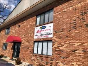 Brick commercial building with red awning and a sign advertising sales, service, and parts