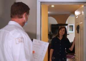 Man at a doorway holding papers talks with a woman standing in the hall