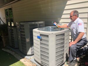 Technician inspecting a large outdoor HVAC unit beside a house