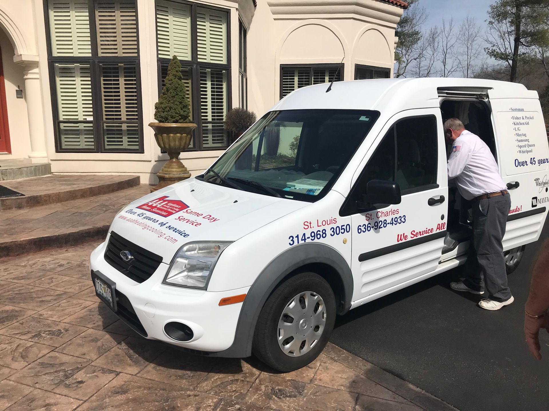 White service van parked outside a building, with a person leaning into the open driver’s door.