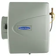 Wall-mounted gray water softener unit with a blue logo and brass valve on the right