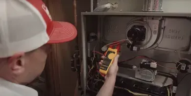 Technician using a multimeter to inspect electrical wiring in a service panel