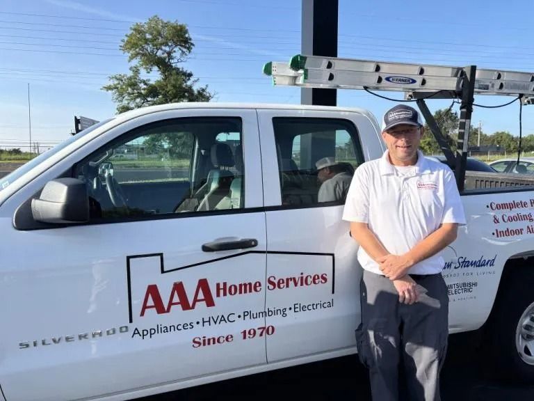 AAA Home Services technician standing beside a white service truck on a sunny street