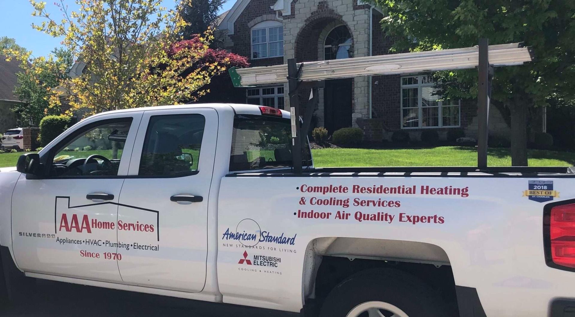 White service pickup truck with company logos and text parked in front of a house