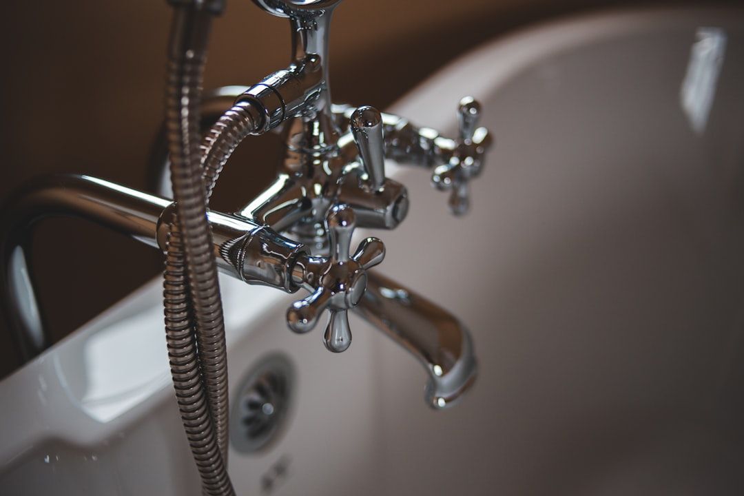 Chrome bathroom faucet over a white sink with running water