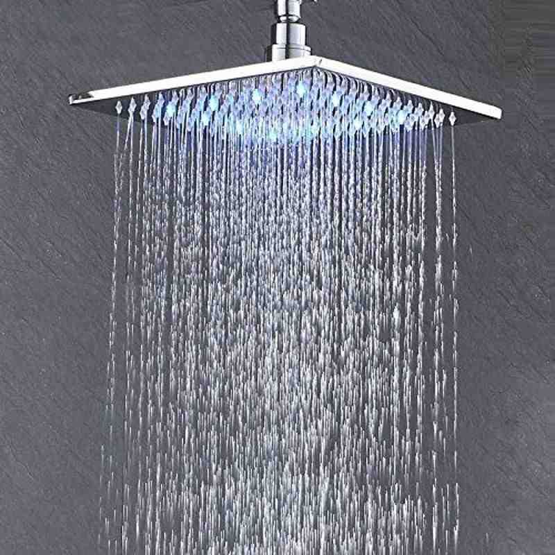 Modern square rainfall showerhead with water spraying down against a gray wall