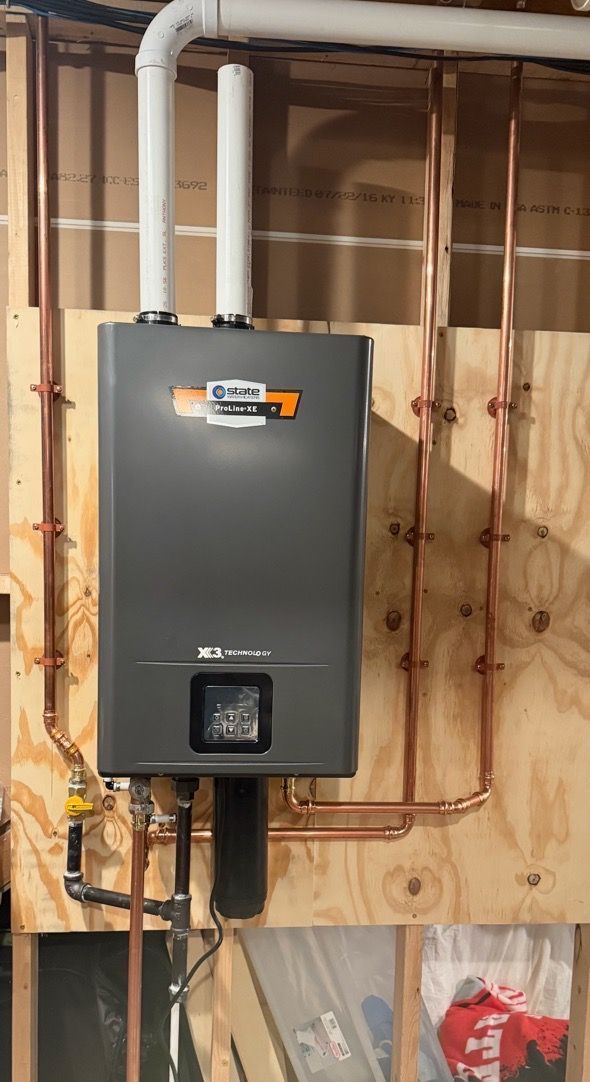 Wall-mounted gray furnace with visible copper pipes in an unfinished basement.