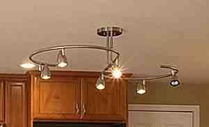 Curved track lighting fixture above wooden kitchen cabinets and a doorway