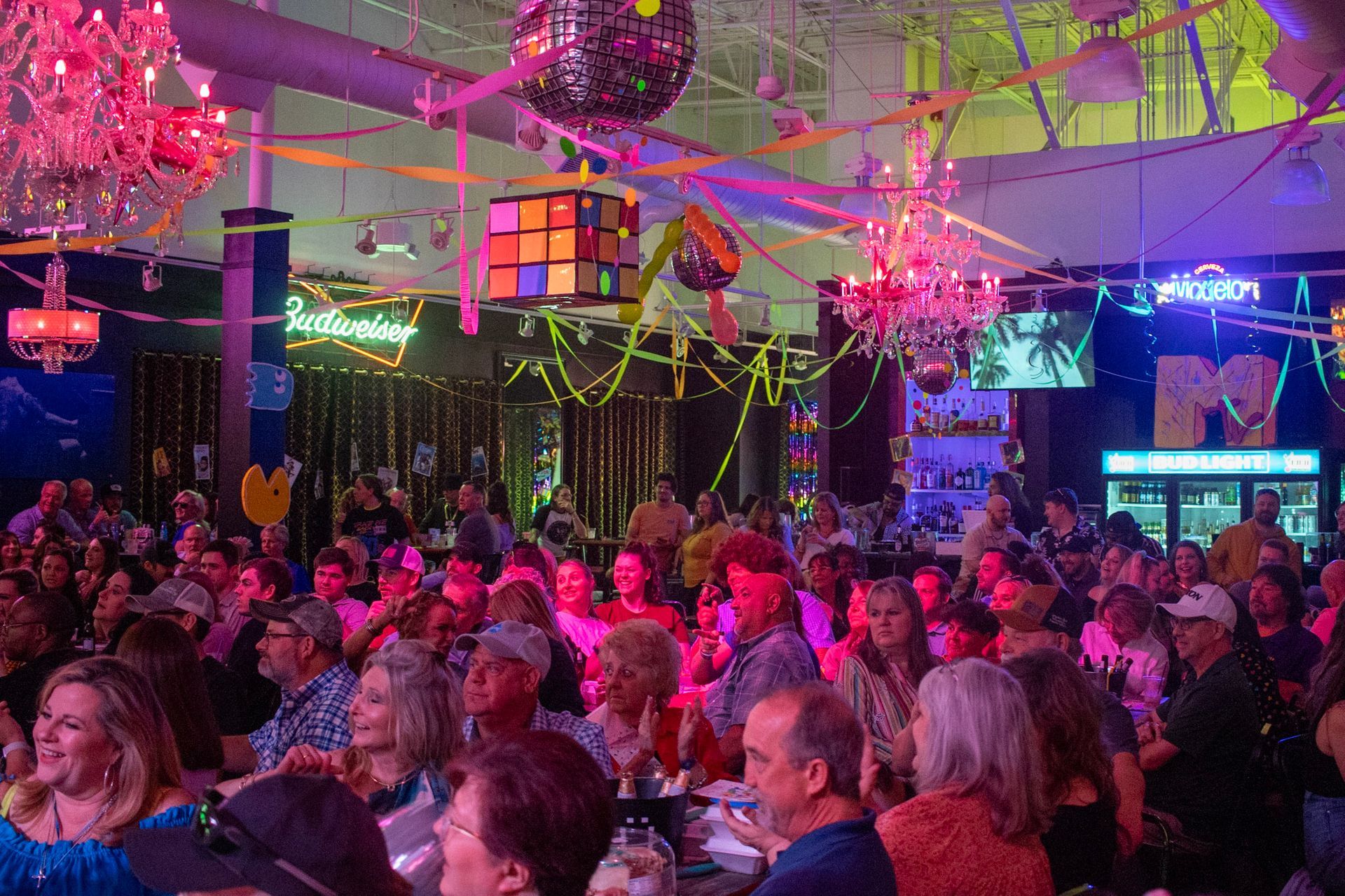 A large crowd of people are sitting at tables in a restaurant.