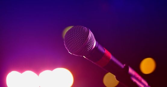 A close up of a microphone on a stage with purple lights in the background.