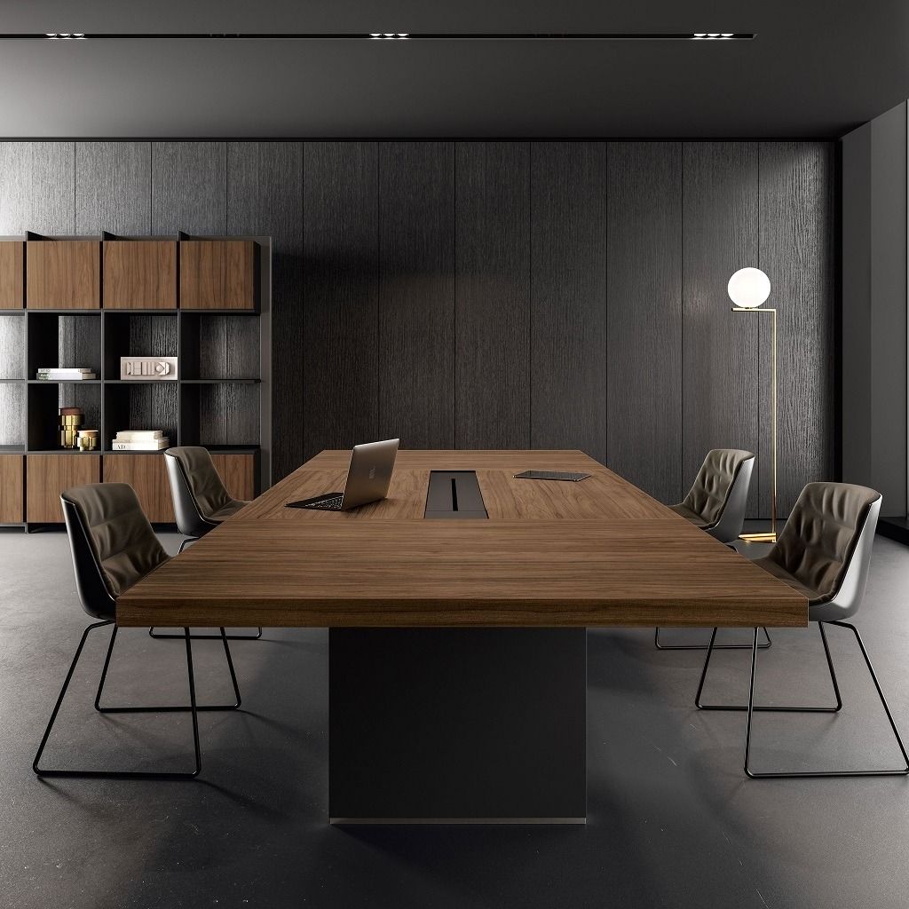 Una moderna sala riunioni con un lungo tavolo in legno, sedie in pelle, una libreria e una lampada da terra su una parete scura e texturizzata.