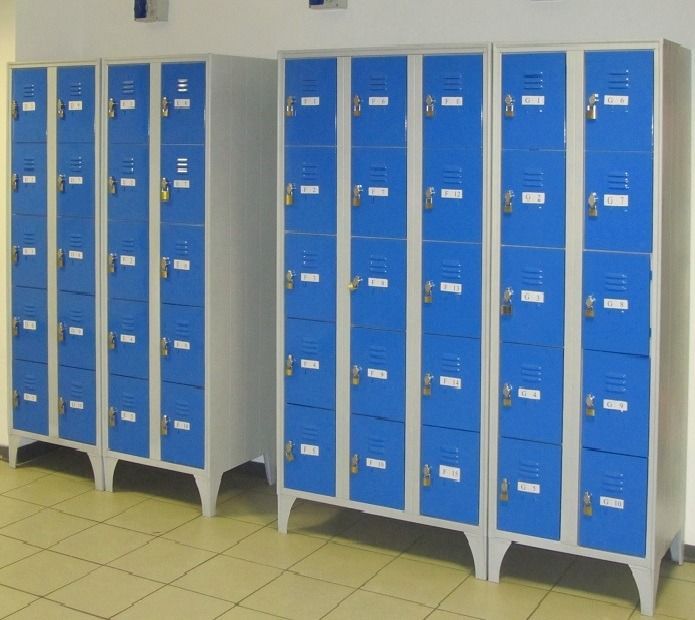 Due armadietti alti di colore grigio con diversi scomparti ante blu, in una stanza con pavimento piastrellato.