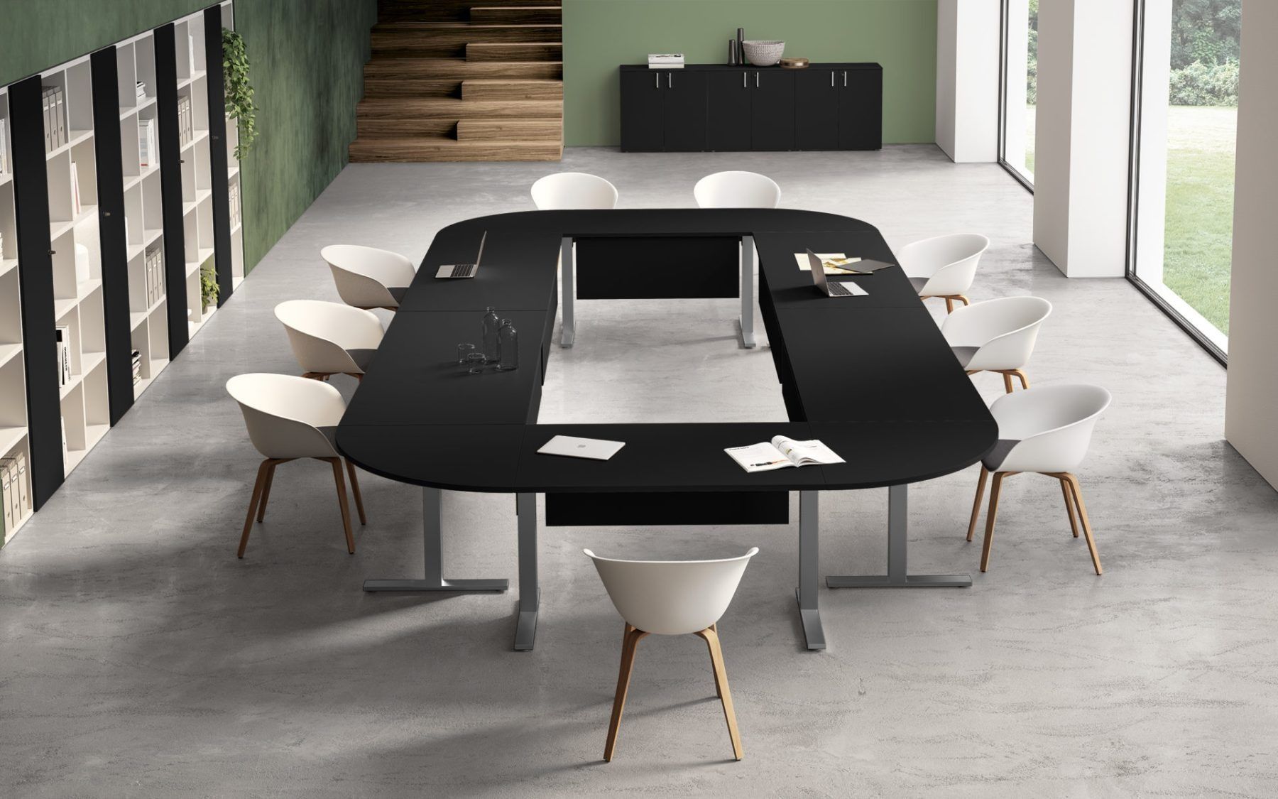 Un tavolo da conferenza nero a forma di U con sedie bianche in un ufficio moderno e minimalista con una parete verde.