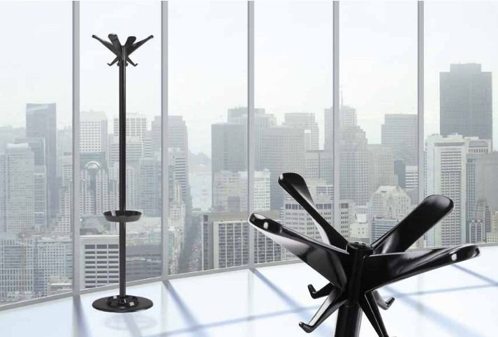 Un appendiabiti alto e nero si erge accanto a un primo piano di un appendiabiti simile, nero e a forma di stella, all'interno di un grattacielo adibito a uffici.