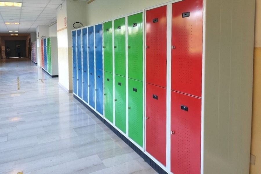 Un corridoio fiancheggiato da alti armadietti metallici dipinti in sezioni di blu, verde e rosso.