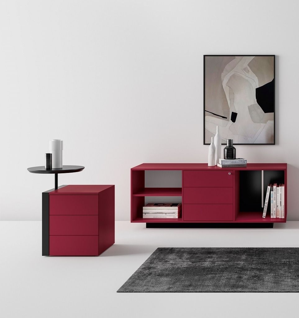 Una consolle minimalista color bordeaux e un tavolino abbinato con piano circolare nero, posizionati contro una parete bianca.