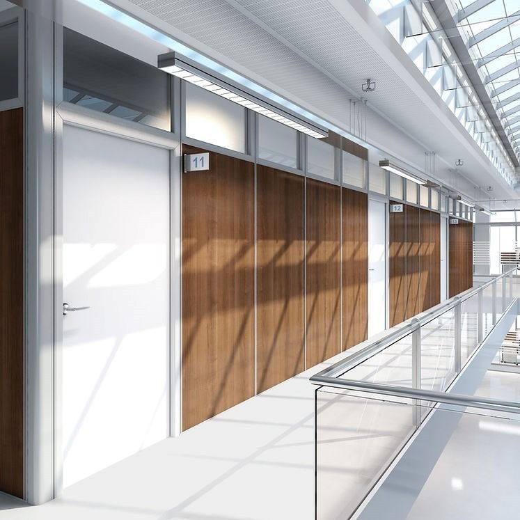 Un corridoio luminoso con porte bianche, pannelli in legno e una ringhiera in vetro che si affaccia su uno spazio aperto.