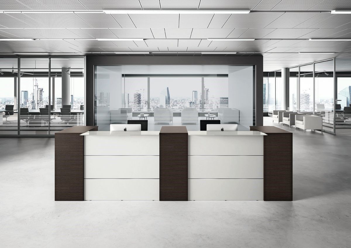 In un luminoso spazio di lavoro minimalista, si trova un moderno bancone reception con superficie bianca e dettagli in legno scuro.