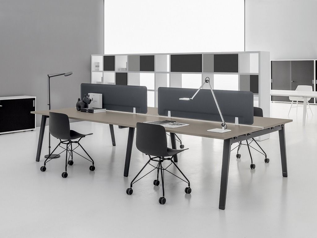 Un ufficio moderno con due lunghe scrivanie in legno, sedie da ufficio nere, paraventi grigio scuro e lampade minimaliste.