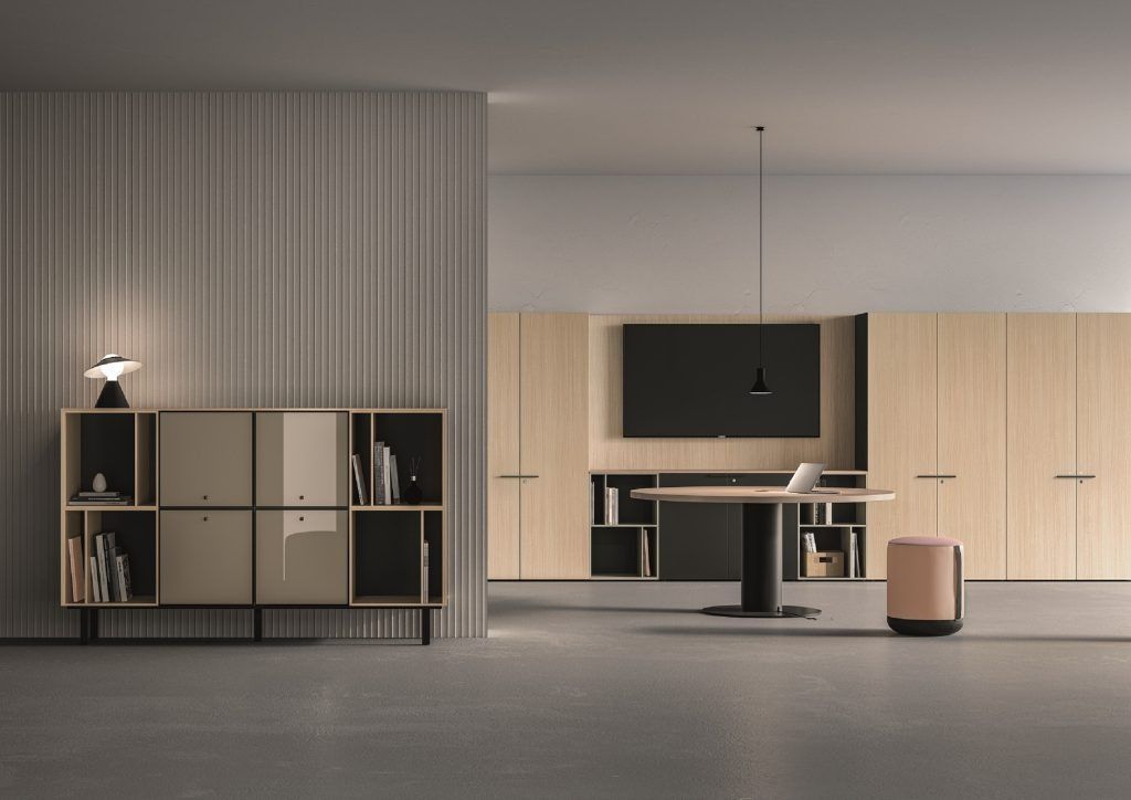 Un moderno interno per ufficio caratterizzato da un'elegante scaffalatura, una scrivania circolare, vani portaoggetti a parete e una lampada a sospensione minimalista.