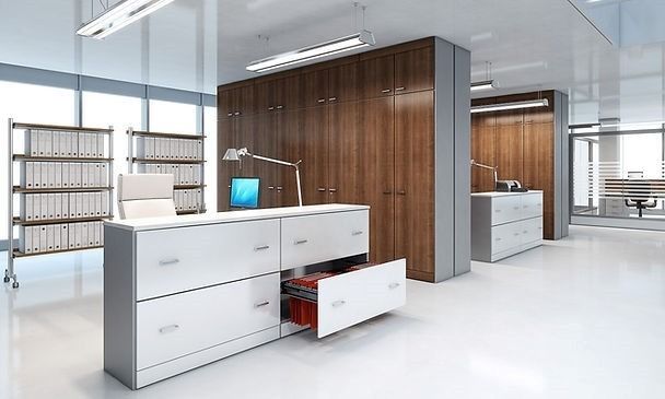 Un ufficio moderno con schedari bianchi dotati di un cassetto a giorno, pareti attrezzate in legno e ripiani in metallo per i raccoglitori.