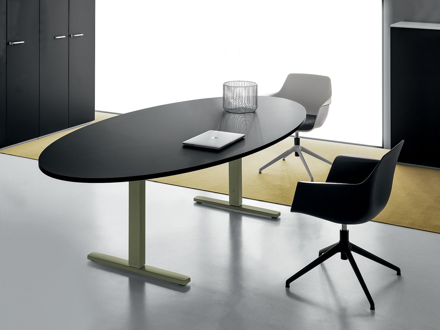 Un tavolo da riunione ovale nero con due sedie, una nera e una grigia, in un ambiente d'ufficio minimalista.