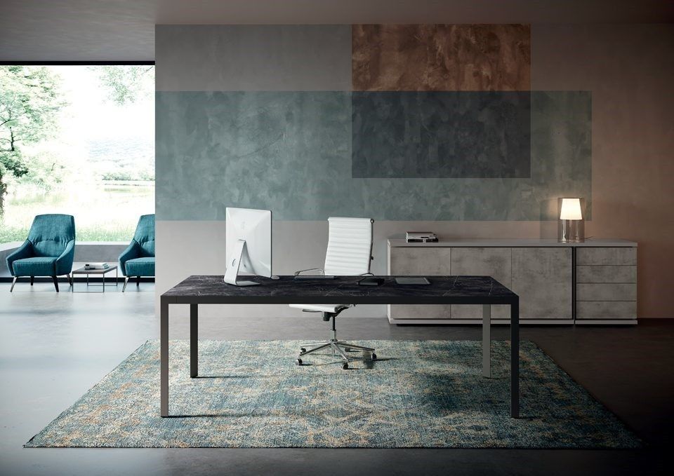 Un ufficio moderno con scrivania nera, sedia bianca e tappeto, addossato a una parete decorata con blocchi di colore astratti.