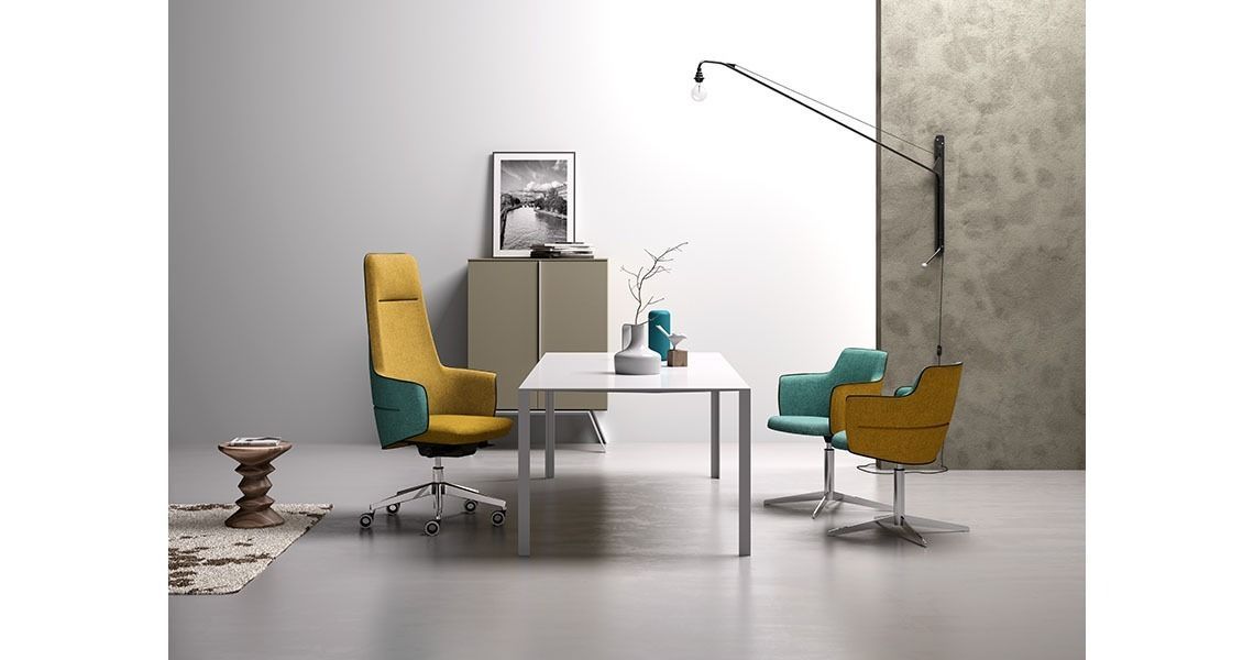 Postazione di lavoro moderna in ufficio con sedia da ufficio gialla e turchese, un set di sedie più piccole abbinate e un tavolo bianco.