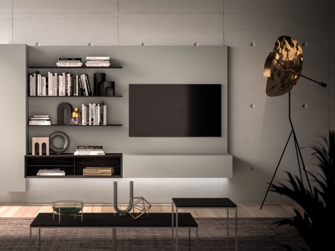 Un soggiorno moderno con TV a parete, scaffali a vista con libri, oggetti decorativi e un'originale lampada da terra dorata su un tappeto.