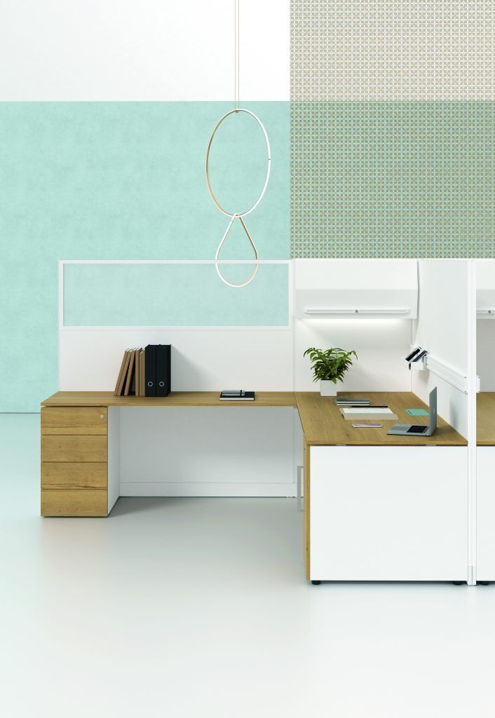 Una moderna postazione di lavoro in ufficio con scrivania bianca e in rovere, mobiletto laterale, una piccola pianta in vaso e pareti color verde acqua.