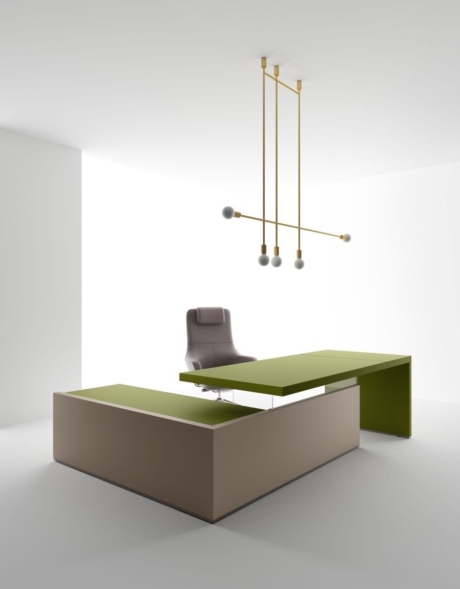 Un ufficio minimalista con una sedia grigia, una scrivania a L nei toni dell'oliva e del beige e un moderno lampadario in ottone in una stanza bianca.