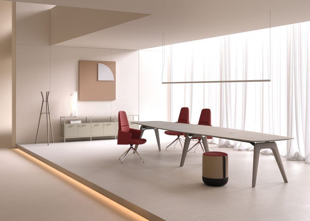 Sala conferenze in stile minimalista con un lungo tavolo bianco, sedie rosse, uno sgabello rotondo e tende bianche a tutta altezza.