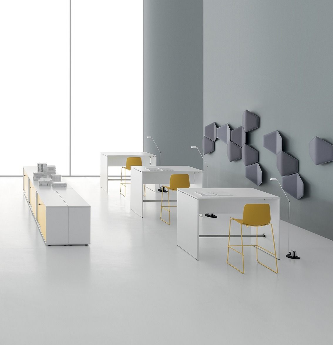 Ufficio minimalista con tre scrivanie bianche e sedie color giallo senape, oltre a pannelli acustici geometrici su una parete grigia.