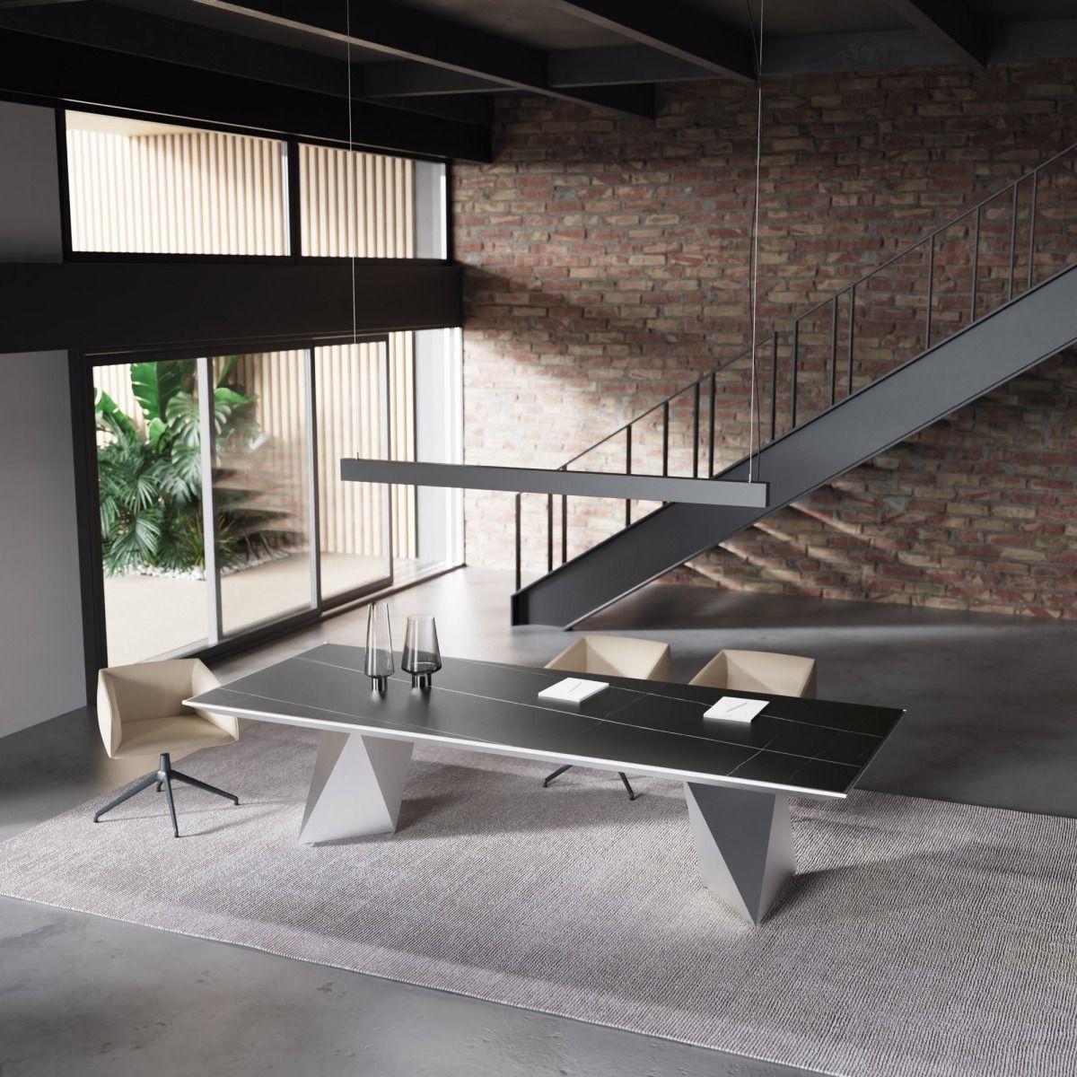 Sala da pranzo moderna con un lungo tavolo nero, basi geometriche argentate e sedie su un tappeto, addossate a una parete di mattoni e a una scala.