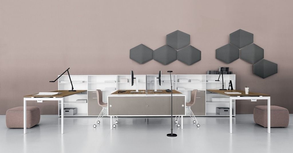 Una configurazione di scrivania da ufficio contemporanea con struttura bianca, superfici in legno, ripiani portaoggetti e decorazioni murali esagonali.