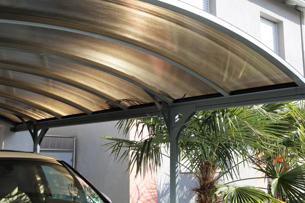 A Car Is Parked Under a Canopy Next to A Palm Tree — Bundy Tiny Homes and Carports in Childers, NSW