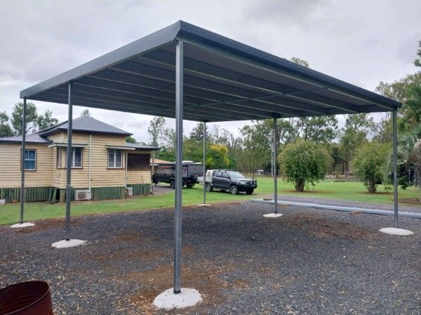 Aluminium Carport with White Building and Small Plants Behind — Bundy Tiny Homes and Carports in Branyan, QLD