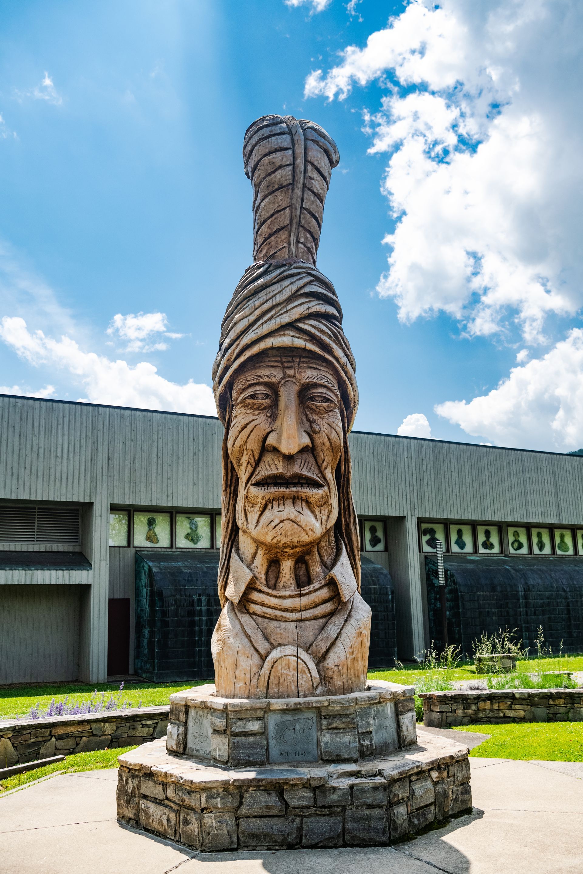 Wooden Native American statue outside a building on a sunny day.