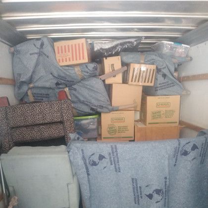 A moving truck filled with boxes and a chair.