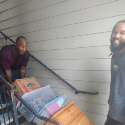 Two men are moving boxes down a set of stairs.
