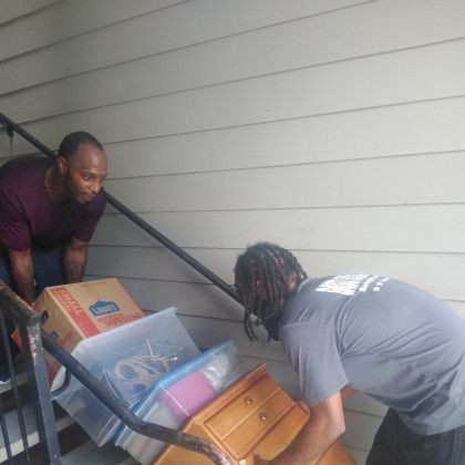Two men are moving a dresser up a set of stairs.