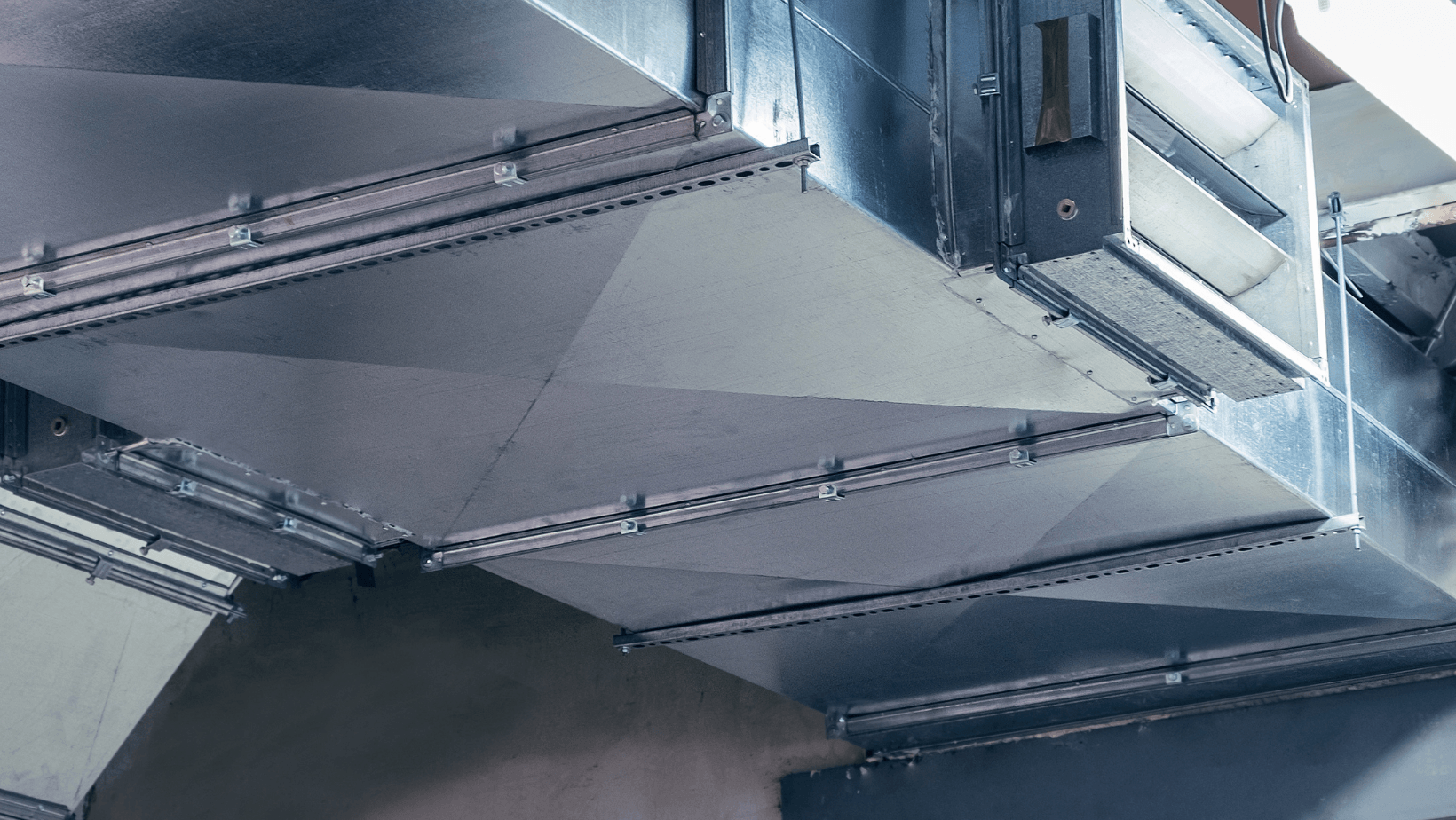 A close up of a metal duct hanging from the ceiling of a building.